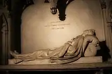 Photographie couleur montrant une statue de femme en marbre sur un tombeau.