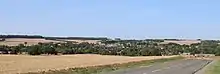 Panorama du village d'Agnicourt, au premier plan, niché au fond de la vallée de la Serre,  avec le clocher de l'église qui émerge en bas à droite. Au loin, le clocher de l'église de Tavaux.