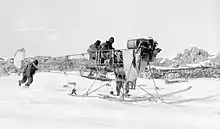 Photo en noir et blanc d'une structure d'avion autour de laquelle s'affairent plusieurs hommes.