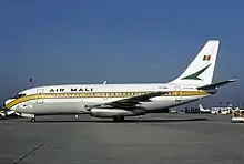 un avion Boeing blanc sur la tarmac avec l'inscription Air Mali et le drapeau malien en arrière