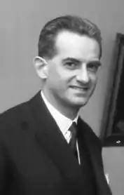 Portrait noir et blanc d'un homme souriant en costume et cravate.