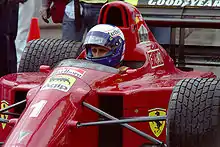 Photo en couleur d'Alain Prost dans le cockpit de sa Ferrari, vu de trois-quarts en plan rapproché.