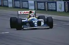Photographie d'une Formule 1 bleue et jaune, vue de face, sur une piste, avec le numéro 2.