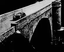Photo d'une voiture rouland sur un pont de pierre.