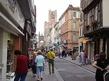 Rue piétonne commerçante à façades en brique rouge ou colombage et briques.