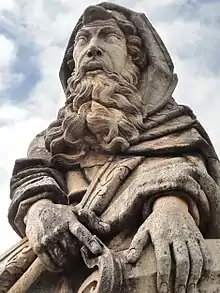 Photographie en couleurs. Gros plan du buste de la statue représentant le prophète Isaïe : sa barbe est bouclée et abondante et ses vêtements sont amples avec de nombreux plis.