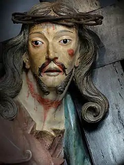 Photographie en couleurs. Gros plan sur le buste de Jésus pendant la montée du Calvaire.