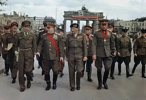 Photo en couleur d'un groupe de treize hommes en uniforme marchant.