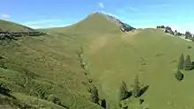 Petit vallon de montagne couvert de prairies verdoyantes et prolongé par un sommet.