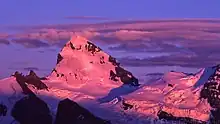 Montagne enneigée rendue rose par la lueur du couché de soleil.