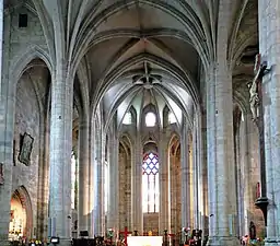 Photographie couleur de la nef et du chœur d'une grande église gothique.