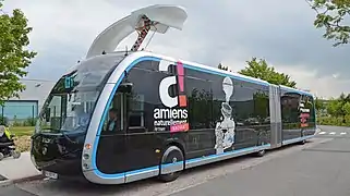 Un bus articulé Irizar du réseau Ametis d'Amiens, en cours de recharge sous une potence spécifique.
