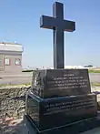 Monument en forme de croix chrétienne en granit gris foncé.