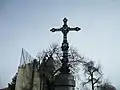 Monument surmonté d'une croix métallique sur la place de l'église. Elle est ornée de décor végétal, d'un médaillon de la Vierge à l'Enfant, d'anges et du monogramme trilitère du nom grec de Jésus "JHS".