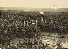 Photographie noir et blanc montrant une foule et l'aumônier au centre.