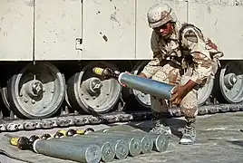 Un militaire américain manipulant un obus-flèche en uranium appauvri M833 de 105 mm durant l'opération Bouclier du désert. La pointe du M833 est recouverte d'un embout protecteur en polystyrène.