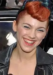 Femme rousse d'environ 25 ans, très souriante.