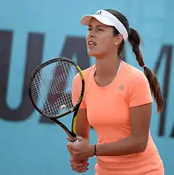 Une joueuse de tennis tenant sa raquette devant elle à deux mains.