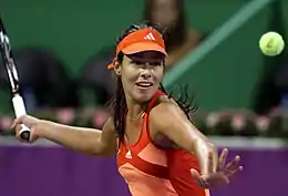 Une joueuse de tennis, concentrée, fixe la balle jaune des yeux, et prépare un coup droit.