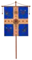 Image montrant un drapeau accroché à une hampe, il se compose d'une croix blanche encadrée de quatre carrés bleus.
