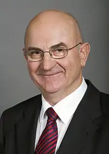 Portrait d'un homme chauve portant des lunettes.