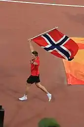 Photographie de Andreas Thorkildsen brandissant le drapeau norvégien