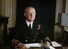 Photo d'un homme assis à un bureau, portant un uniforme d'officier de la marine