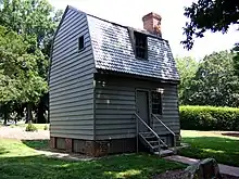 Cabane en bois à deux étages avec une porte d'entrée en haut d'un petit escalier.