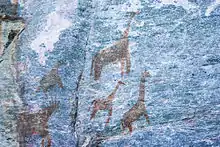 peinture sur roche figurant des quadrupèdes à longs cous, en brun sur fond bleu