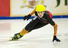 Anna Seidel patinant, la main gauche au sol dans un virage.