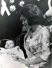 Photographie en noir et blanc montrant une jeune femme de profil tenant un bébé sur ses genoux.