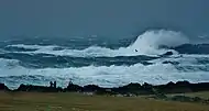 Des lames écumant sur des récifs lors d’une tempête.