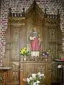 Dans la chapelle, un retable et la statue de saint Piat.
