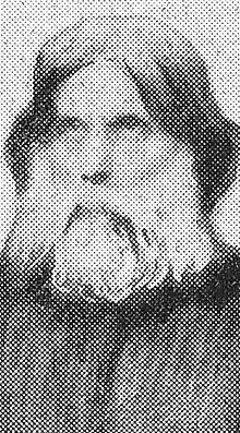 Photographie en noir et blanc représentant Louis Antoine en buste, les cheveux longs et barbu