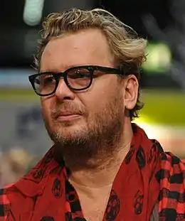 Image d'un homme blanc avec de la barbe et portant des vêtements rouge et une paire de lunette