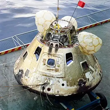 Un vaisseau spatial de forme conique, posé sur le pont d'un bateau.