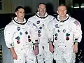 Photographie en couleur de l'équipage d'Apollo 8 en combinaison et sans casque.