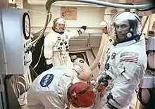 Trois hommes en combinaison spatiale dans un vaisseau spatial.