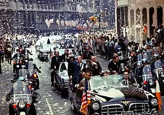 Photographie en couleur des astronautes d'Apollo 11 dans une voiture paradant dans les rues remplies de spectateurs.