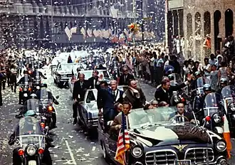 Photographie en couleur de l'équipage d'Apollo 11 lors d'une parade véhiculée en ville.