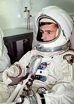 Photographie couleur d'un astronaute en combinaison avec la visière de son casque ouverte.