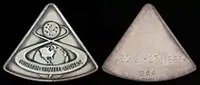 Deux médailles de forme triangulaires, sur celle de gauche le trajet Terre-Lune d'Apollo