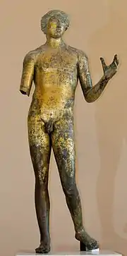 Statue partiellement dorée d'un homme nu, debout, bras gauche demi-levé et bras droit cassé.