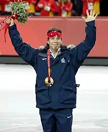 Apolo Ohno, les bras en l'air, avec sa médaille de bronze autour du cou.