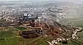 Usine d'agglomération et hauts fourneaux d'Esch-Belval, au Luxembourg. On distingue, derrière les tas de stockage, deux tas d'homogénéisation, celui de gauche étant en train d'être repris par un reclaimer horizontal, en forme de portique de manutention.