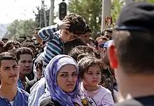 Plusieurs demandeurs d'asiles avec en premier plan une femme et des enfants.