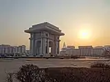 L'Arc de Triomphe à Pyongyang, photographié du nord-est au coucher du soleil en mars 2014. Le bâtiment pyramidal à l'arrière-plan est l'hôtel Ryugyong, le plus haut bâtiment de la Corée du Nord.