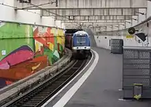 Un train TER, en provenance de Marseille-Saint-Charles, arrive sur la voie unique à quai de la gare d'Arenc-Euroméditerranée, qui est établie dans une tranchée.