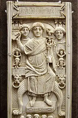 Photographie d'une plaque rectangulaire en ivoire, représentant un homme en tenue d'apparat, surplombé d'une inscription latine.