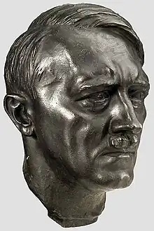 Photo en couleurs (fond gris clair) d’une tête en bronze d’Adolf Hitler, réalisée par le sculpteur Arno Beker, en 1398.